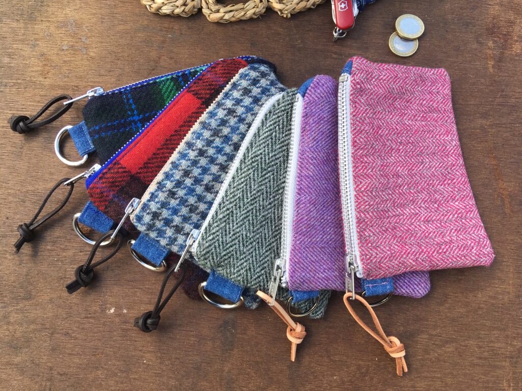 various coin purses made from traditional tweed fabric on a wooden table